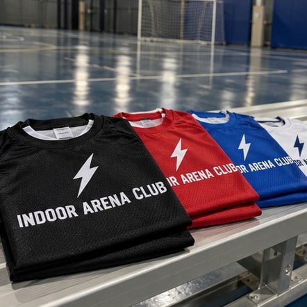 Custom futsal jerseys beside an indoor court
